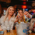 Girls reaching for a bucket of beers