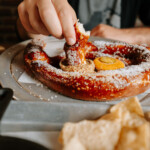 Someone dipping a pretzel into mustard