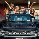 Women posing on a ford bronco